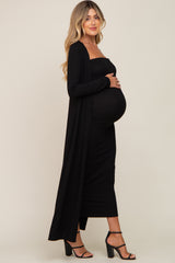 pregnant woman in black ribbed maternity midi dress and matching long cardigan with black heels