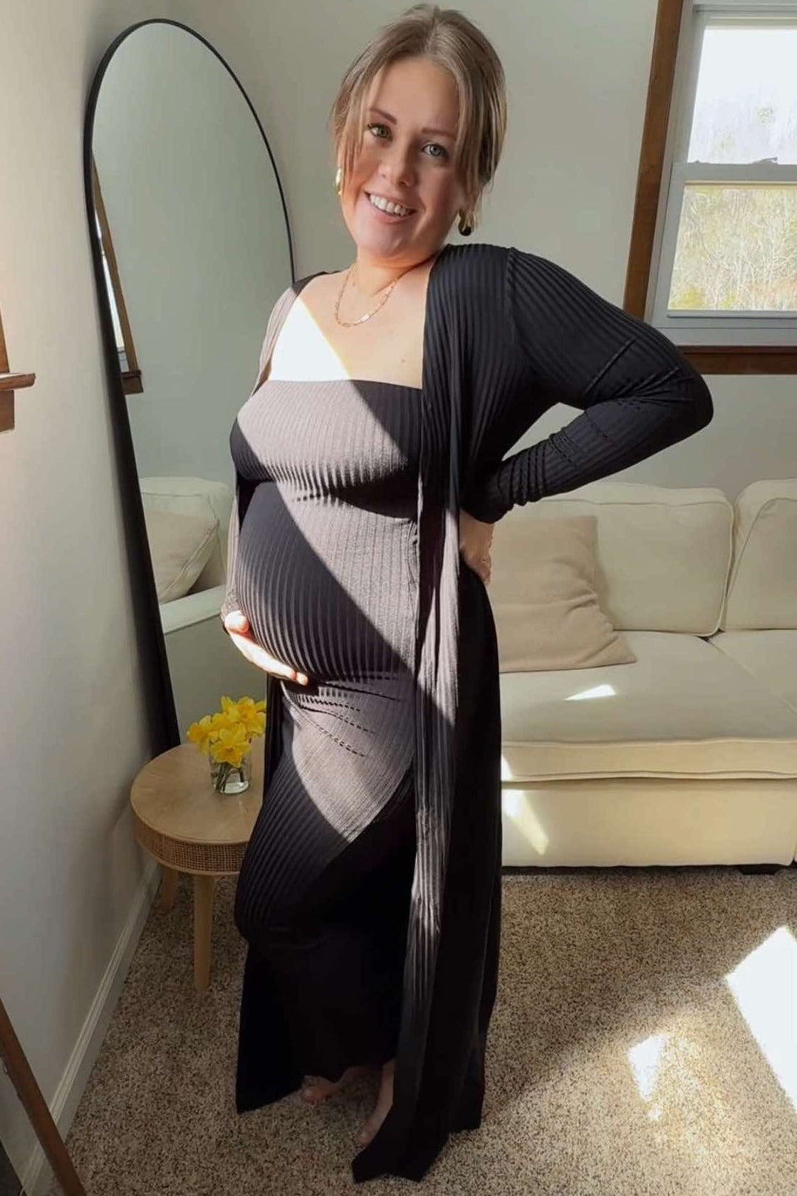 woman wearing a black ribbed maternity dress with a long cardigan, showcasing her baby bump