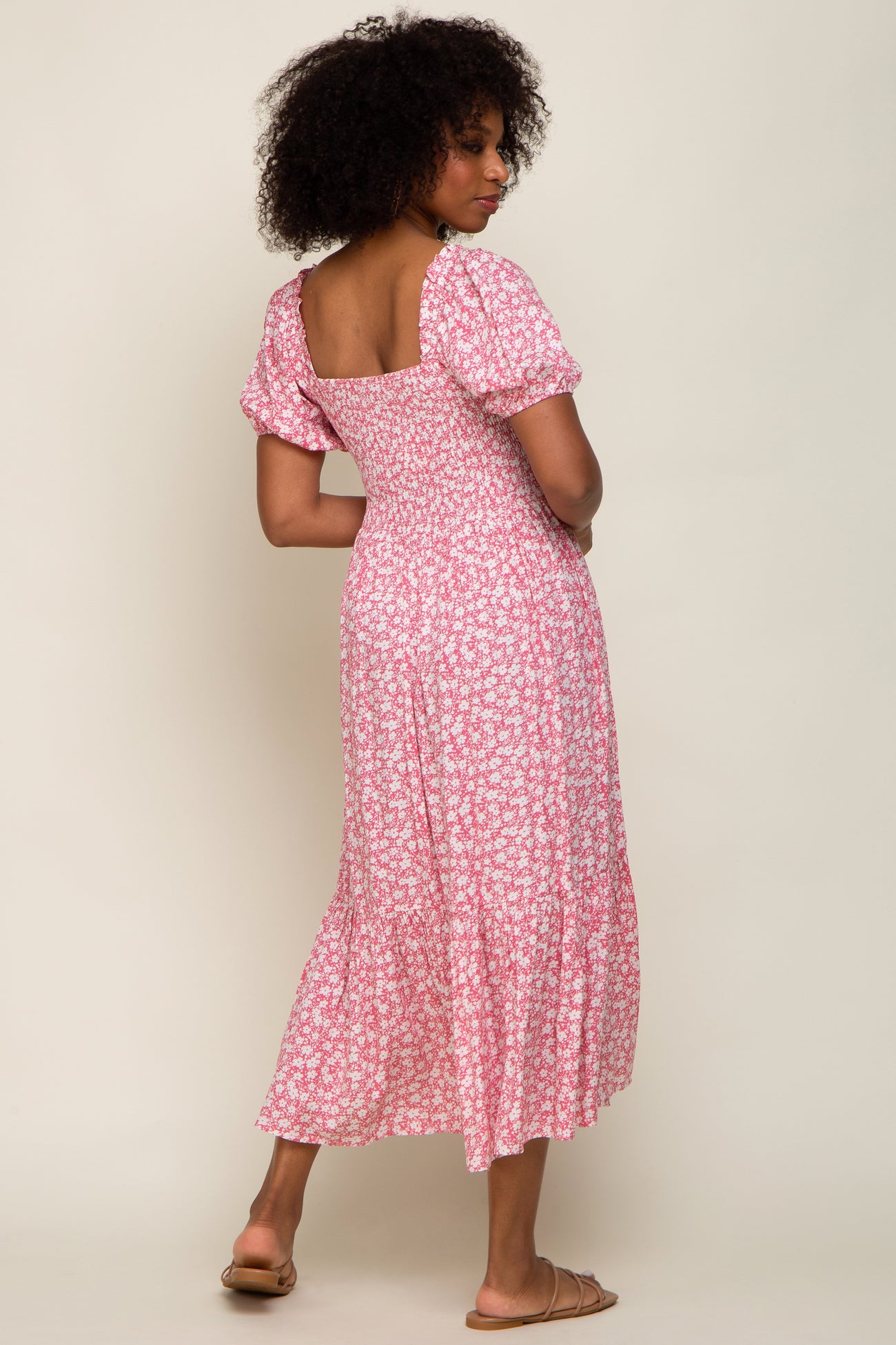 woman wearing a pink floral midi dress with puff sleeves and a squareneck, showing the back view