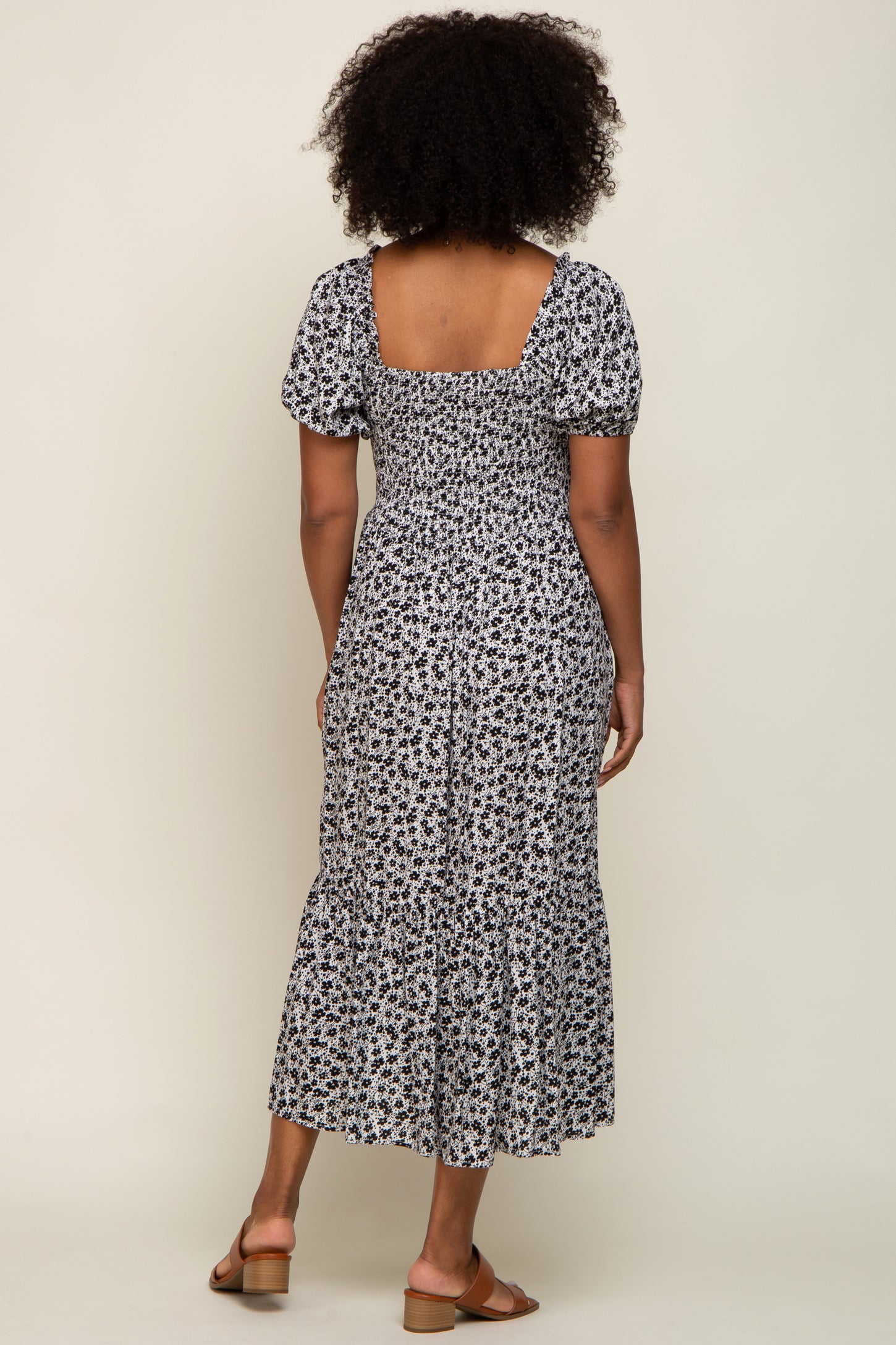 woman wearing a white and black floral print midi dress with puff sleeves and a ruffled hem