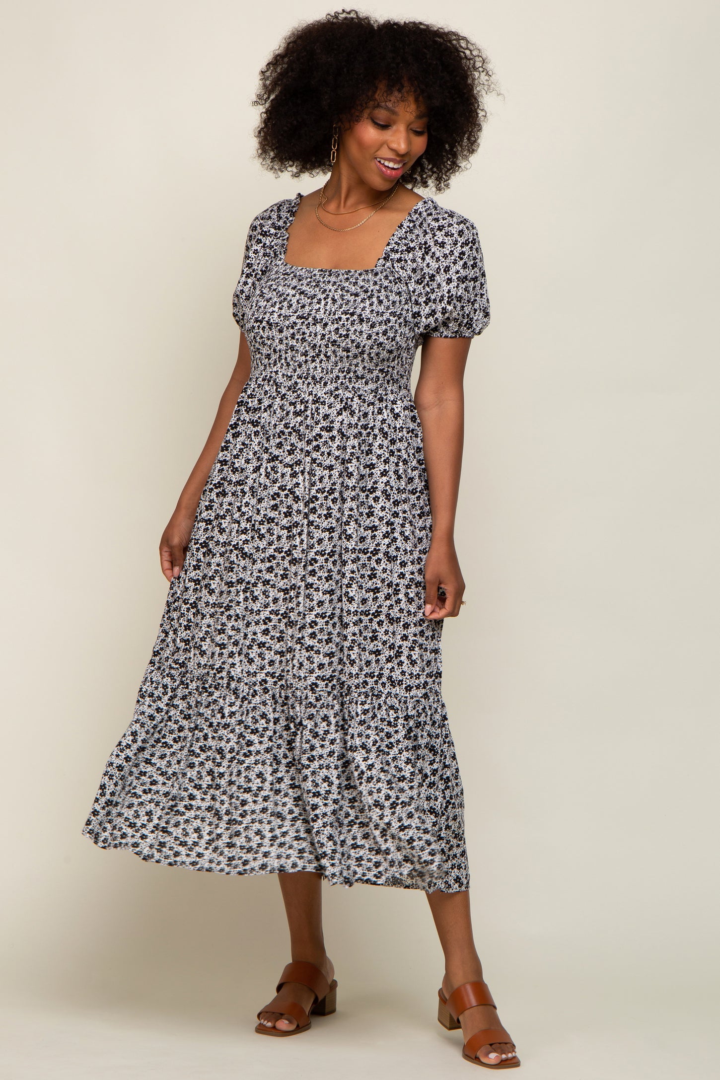 woman wearing a black and white floral print midi dress with puff sleeves and a square neckline