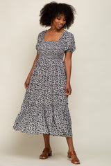 woman wearing a black and white floral print midi dress with puff sleeves and a square neckline