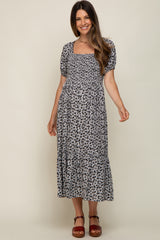 woman wearing a black and white floral print maternity dress with short puff sleeves and a tiered skirt