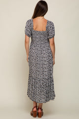 woman wearing a black and white floral maternity dress with puff sleeves and a tiered skirt