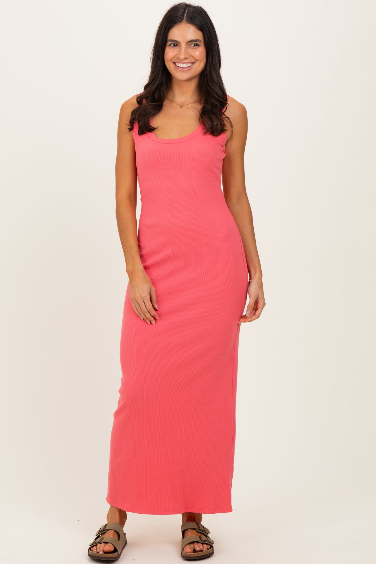 woman wearing a coral pink ribbed maxi dress with a scoop neckline and a slim fit