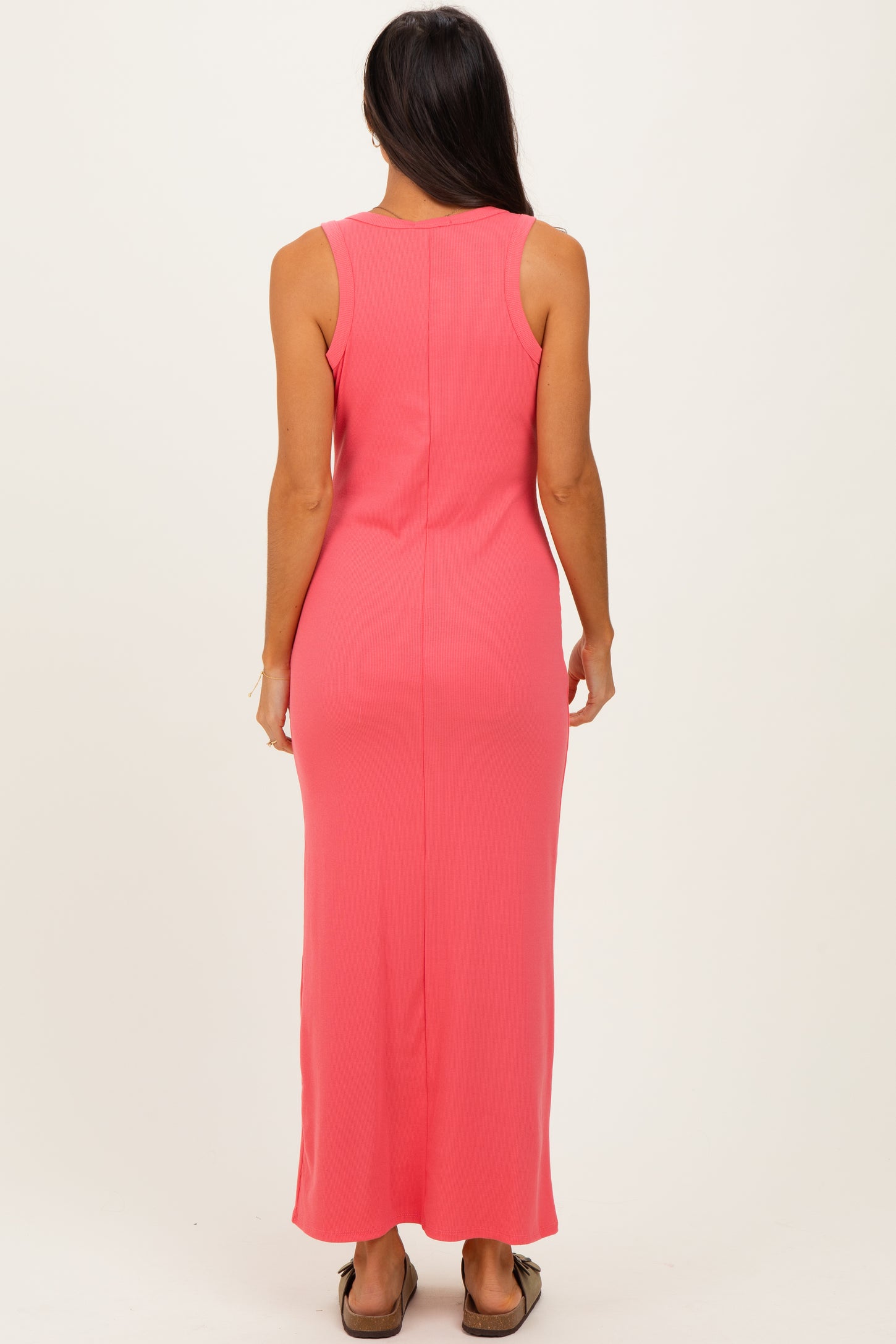 woman wearing a fitted coral sleeveless maxi dress, view from the back
