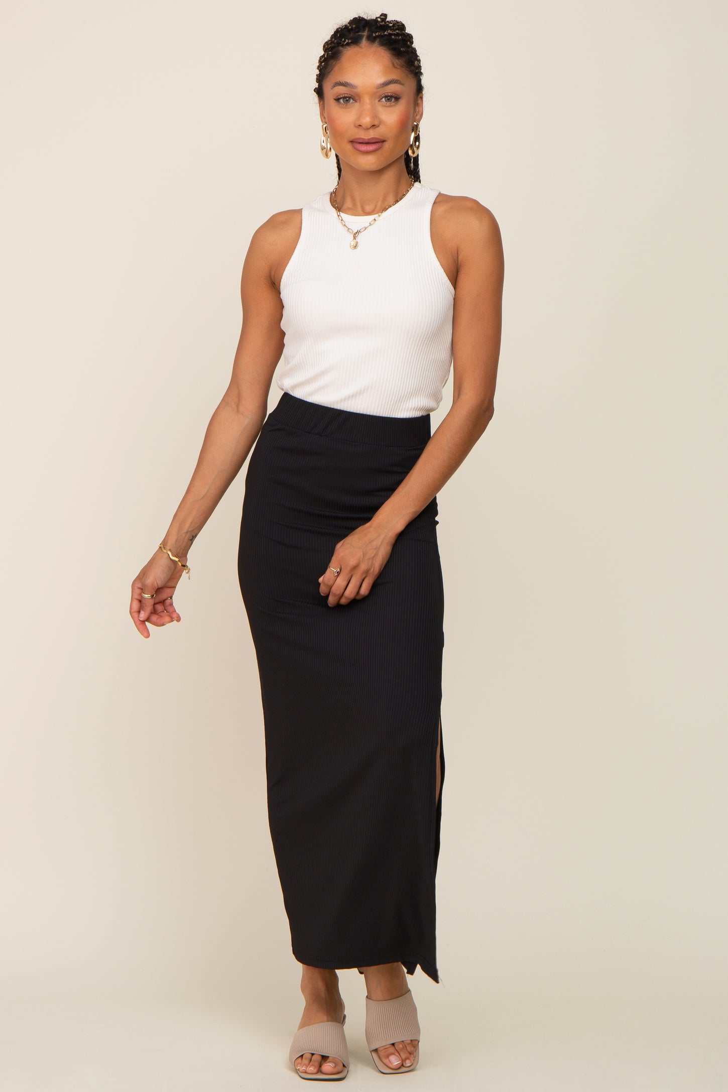 woman wearing a white ribbed sleeveless top and a black maxi skirt with a side slit