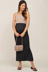 woman wearing a beige and black ribbed maternity maxi dress with a baby bump, holding a small handbag