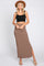 woman wearing a black crop top and a brown ribbed maxi skirt with a side slit, accessorized with a tan hat