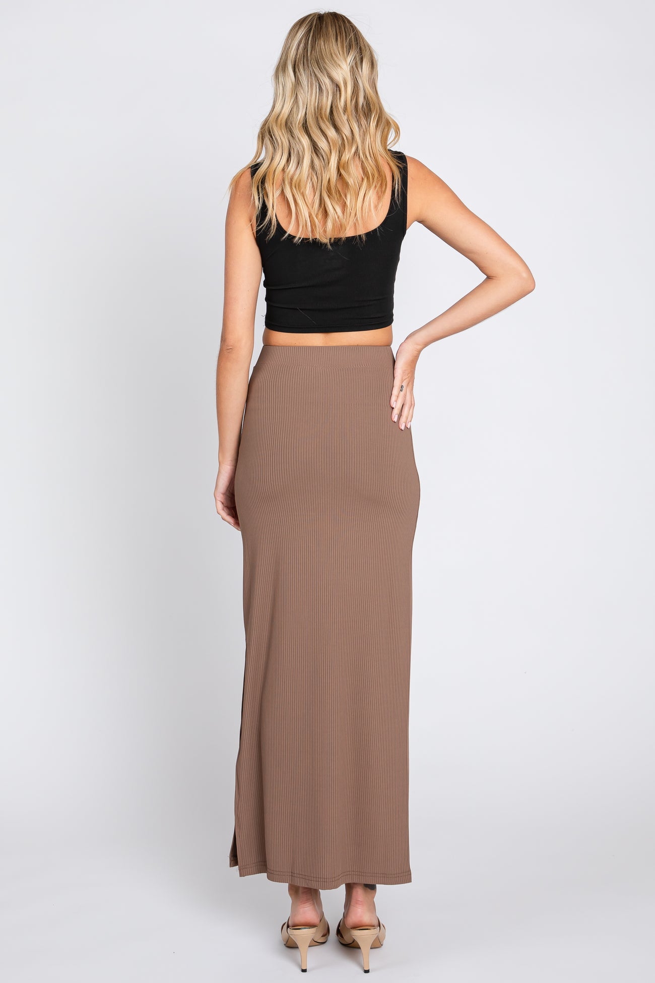 woman wearing a black crop top and a brown ribbed maxi skirt, viewed from the back