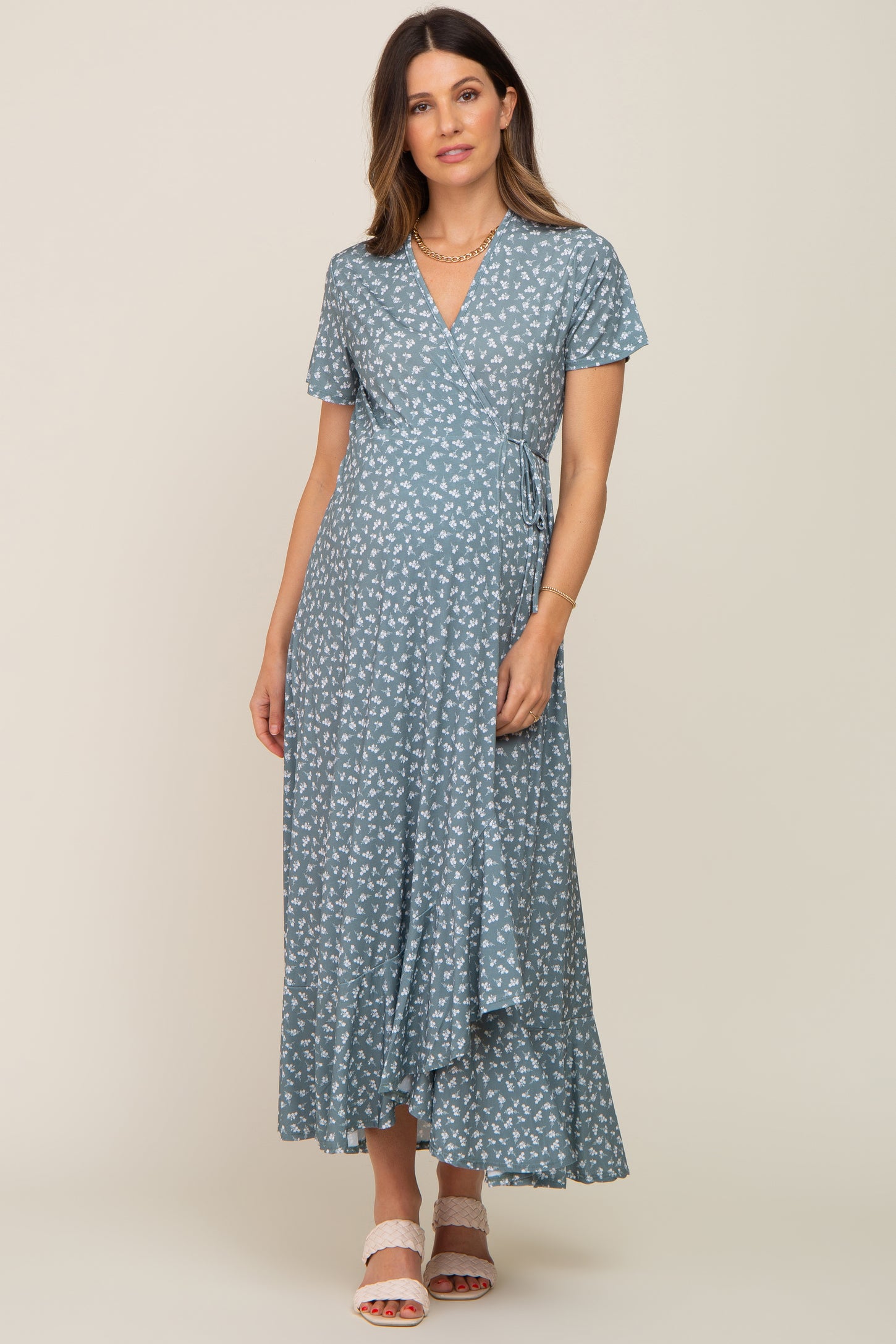 Pregnant woman wearing a blue floral wrap maternity maxi dress with short sleeves and a ruffled hem