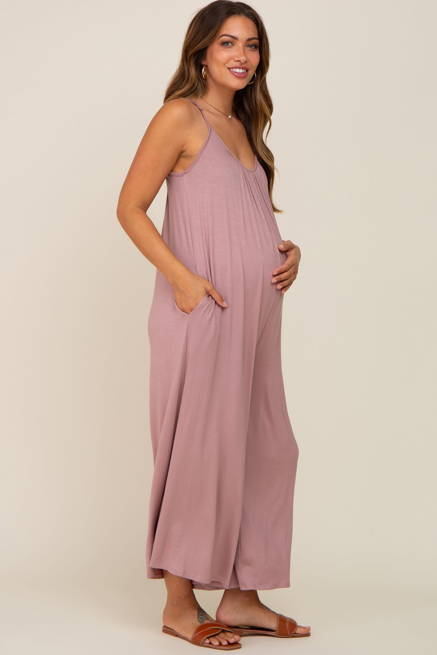 woman wearing a light pink maternity maxi dress with pockets and a visible baby bump