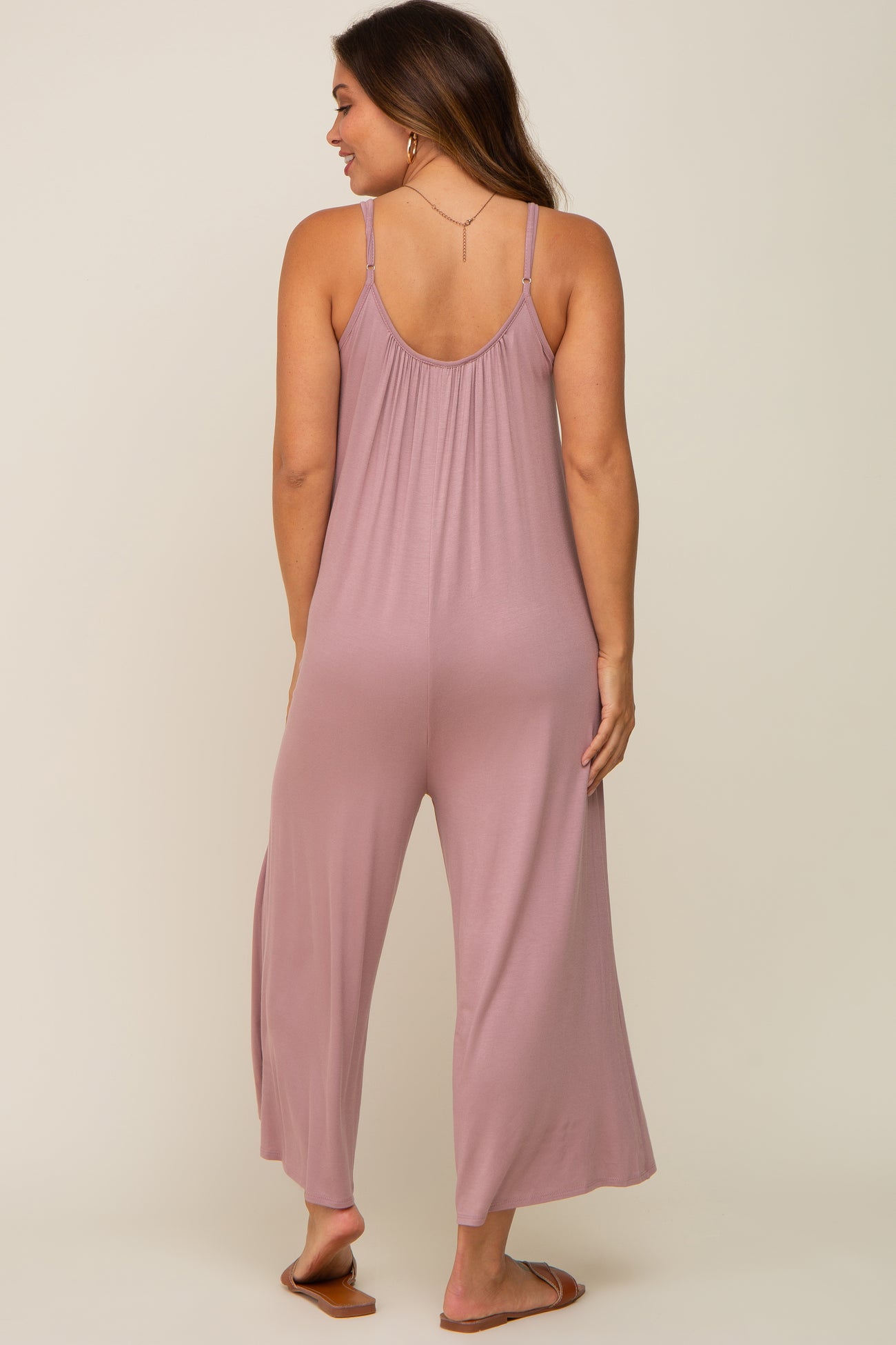woman wearing a mauve maternity jumpsuit with a loose fit and wide leg, showing the back view