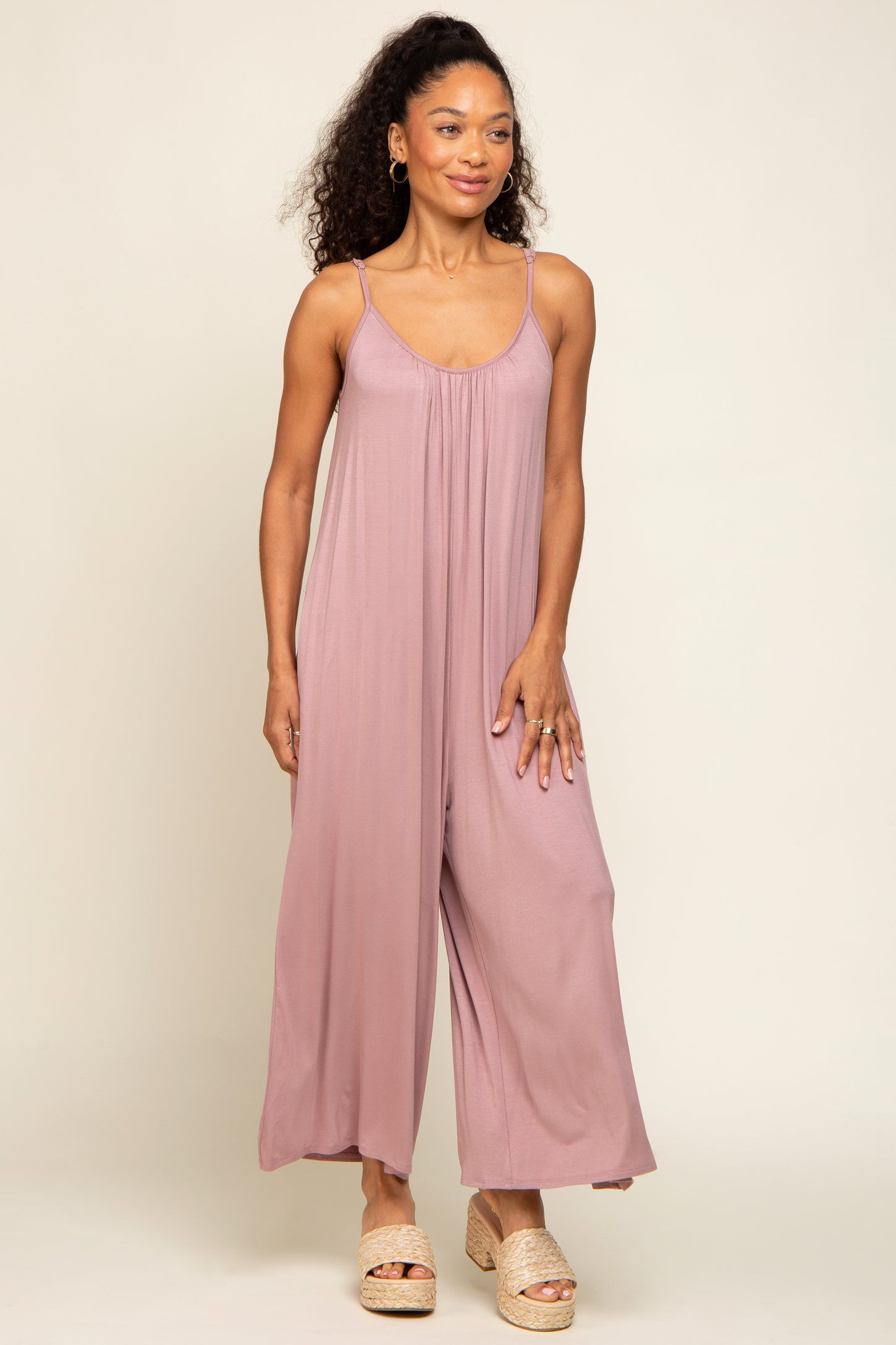 woman wearing a dusty pink sleeveless jumpsuit with wide legs and a relaxed fit