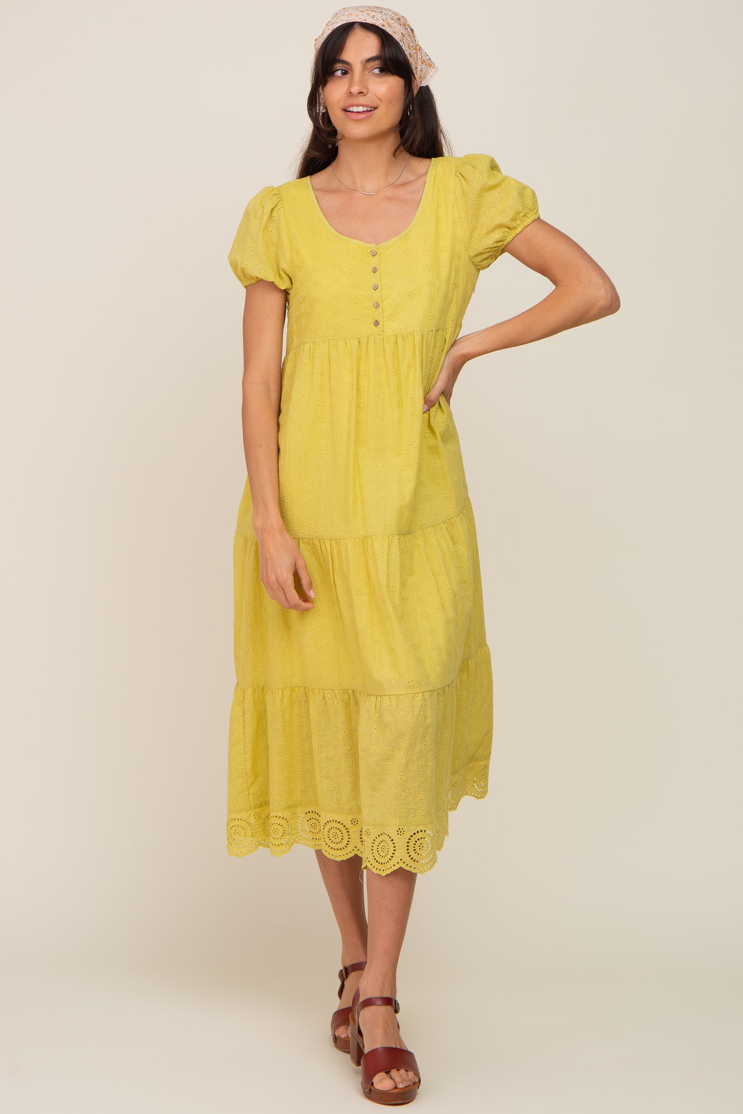 woman wearing a yellow eyelet midi dress with puff sleeves and a floral headscarf