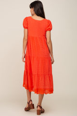 Back view of a woman wearing a red eyelet tiered midi dress with puff sleeves and scalloped hem
