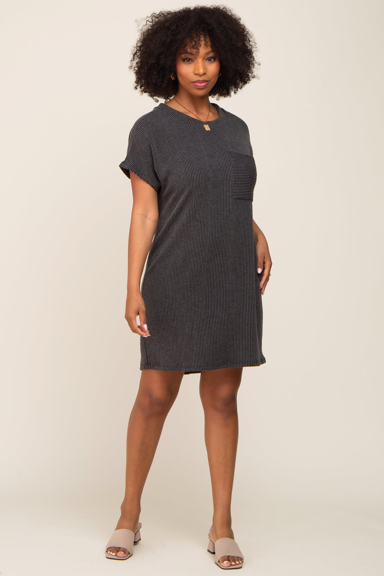 Woman wearing a charcoal grey ribbed short sleeve t-shirt dress with a chest pocket and beige sandals