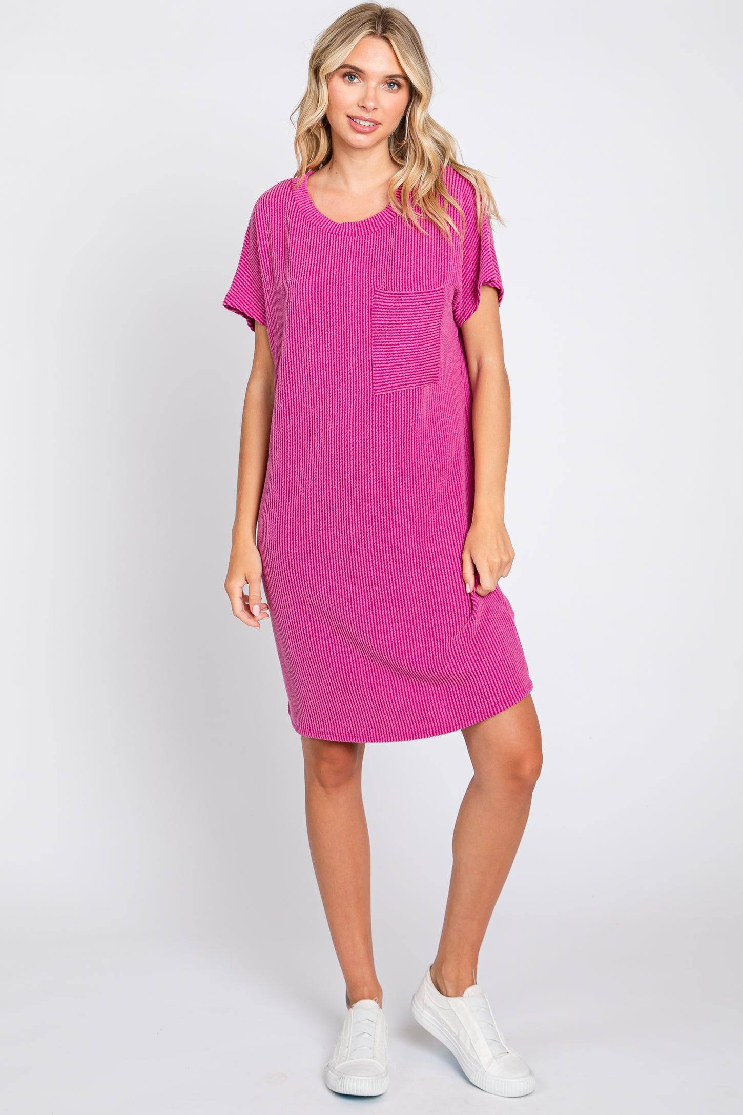 woman wearing a pink striped t-shirt dress with a pocket and white sneakers