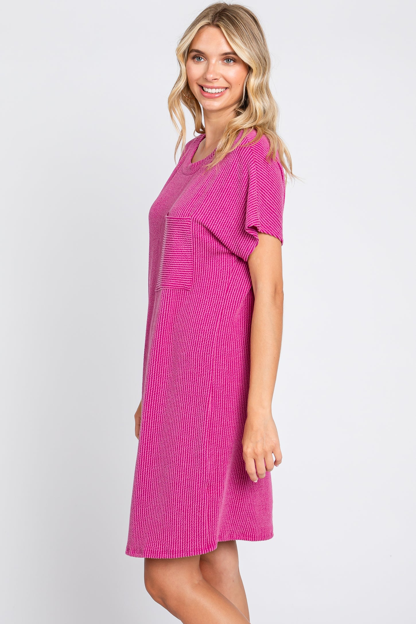 woman wearing a bright pink short sleeve dress with a front pocket and ribbed texture