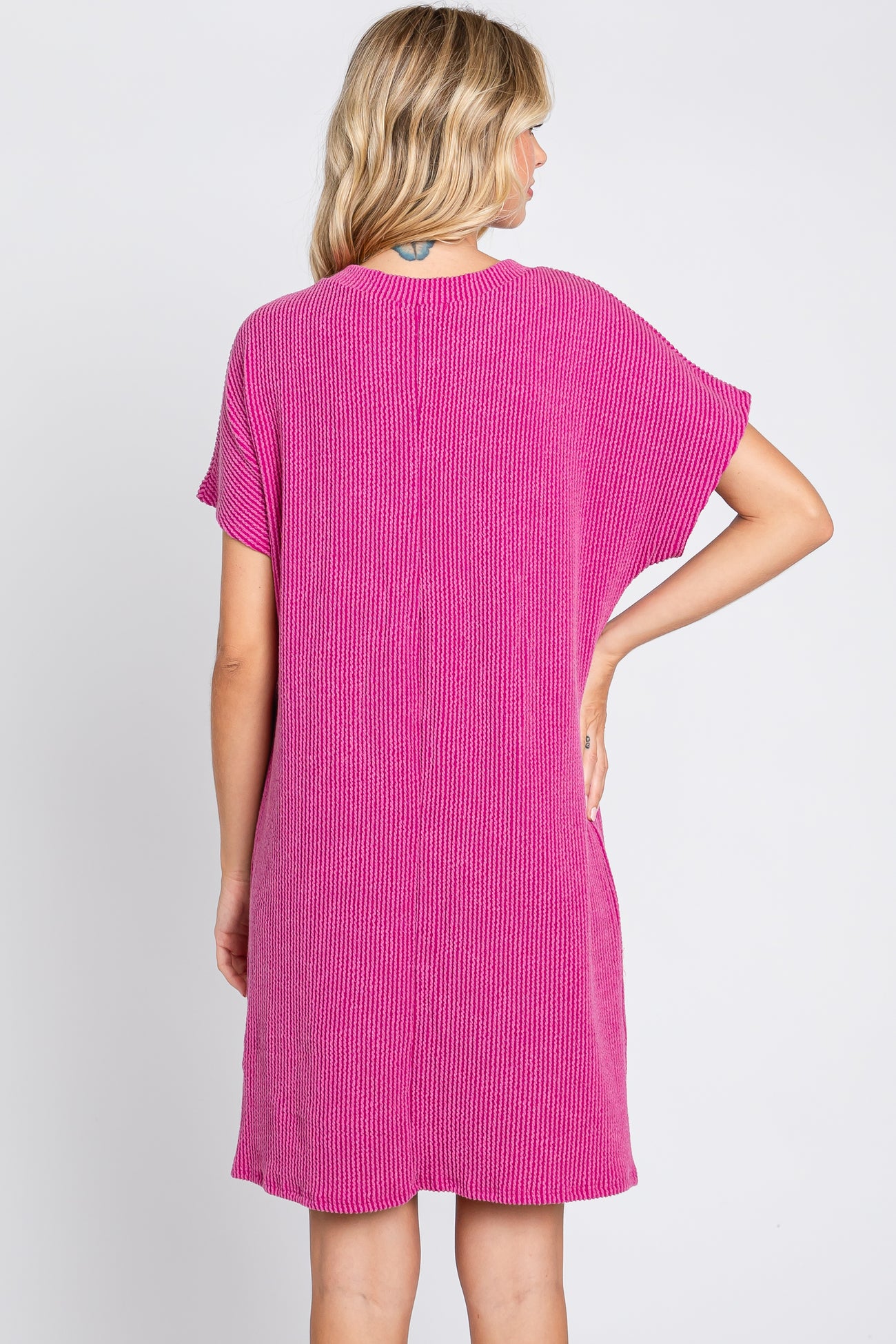 woman wearing a bright pink short sleeve knit dress, viewed from the back