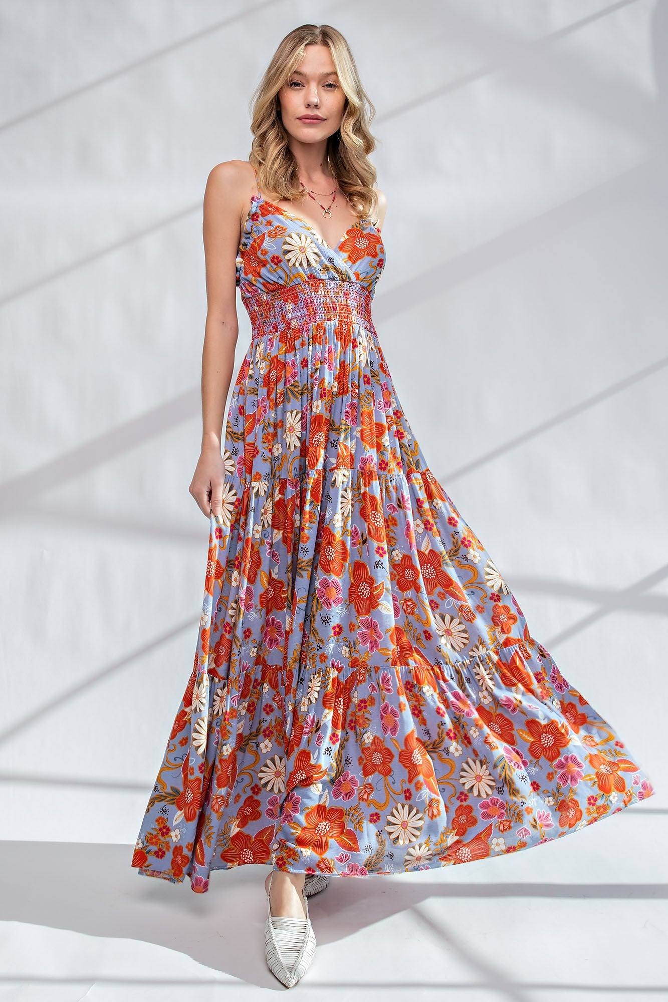 woman wearing a floral maxi dress with a smocked bodice and spaghetti straps, standing against a light background