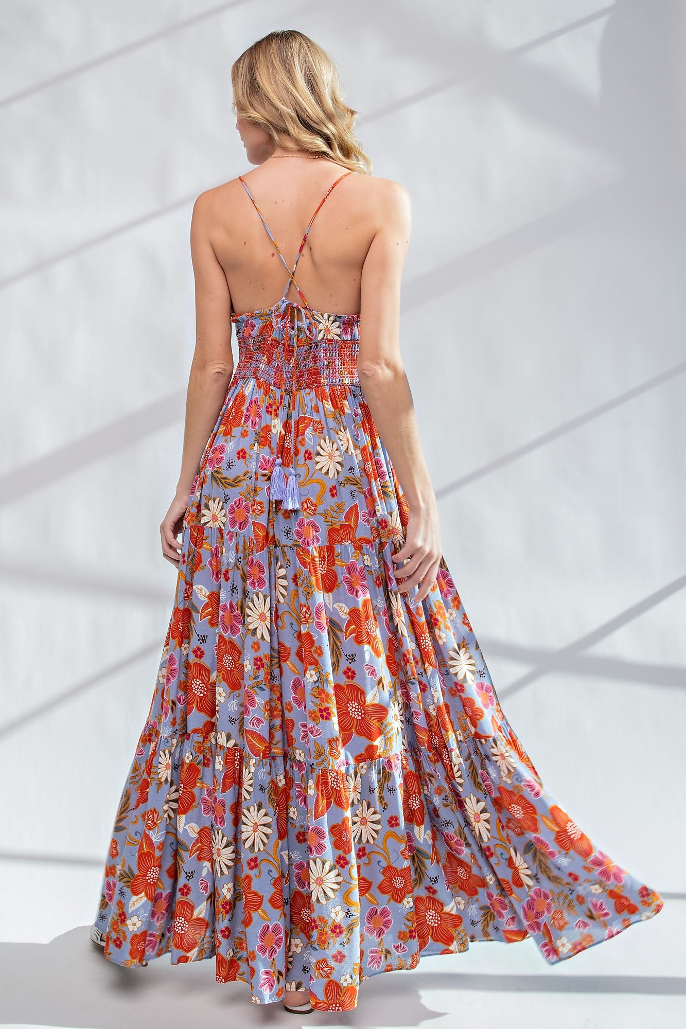 Back view of a woman wearing a floral print maxi dress with spaghetti straps and a tiered skirt