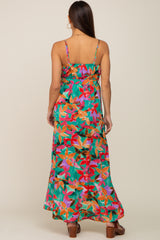 Back view of a woman wearing a green floral print maxi dress with spaghetti straps and a tiered skirt