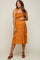 Pregnant woman wearing a mustard yellow floral smocked maternity midi dress and brown platform sandals