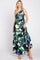 Woman wearing a one-shoulder green and blue floral print maxi dress with a tiered skirt and smocked bodice