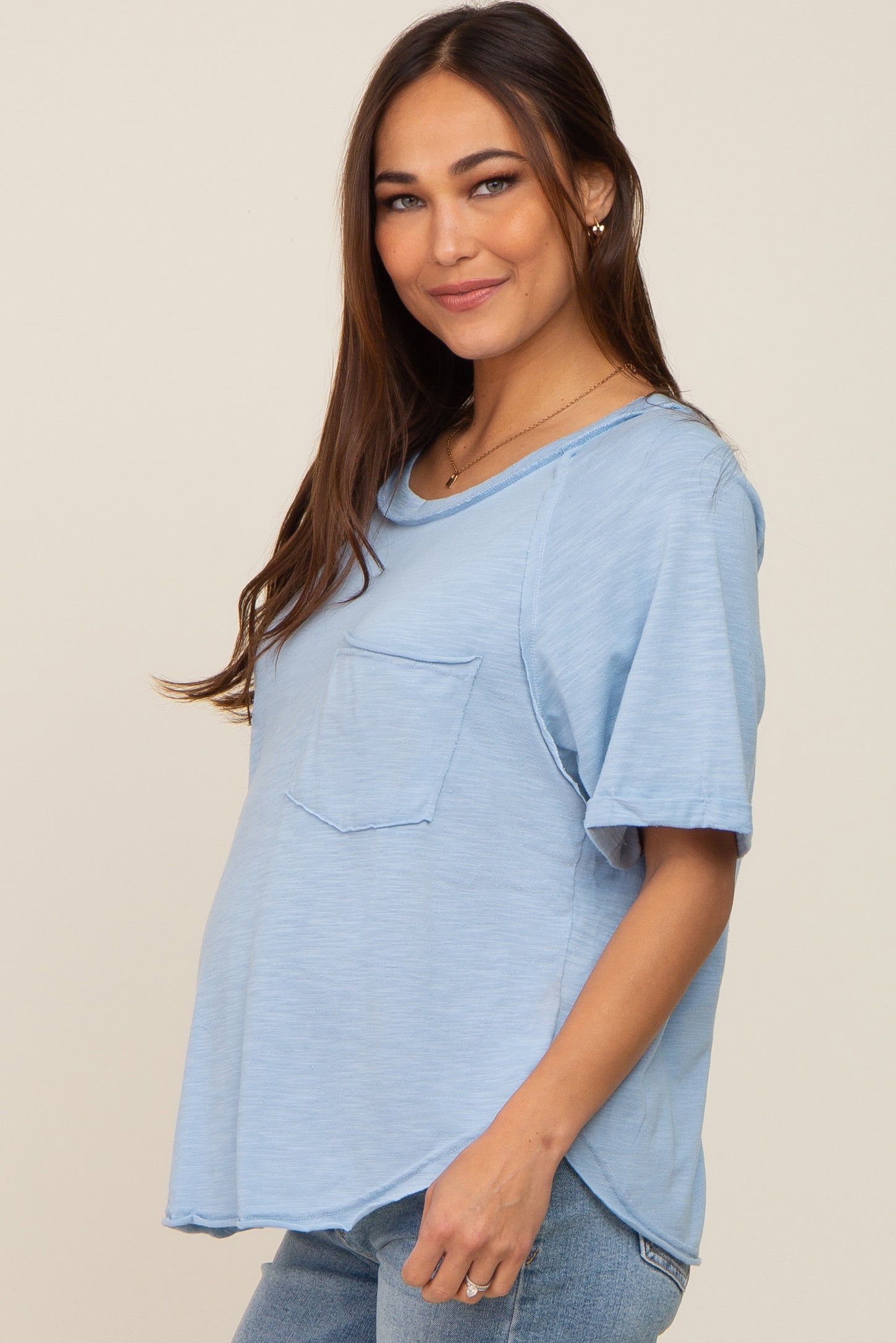 pregnant woman wearing a light blue short sleeve maternity t-shirt with a front pocket and jeans