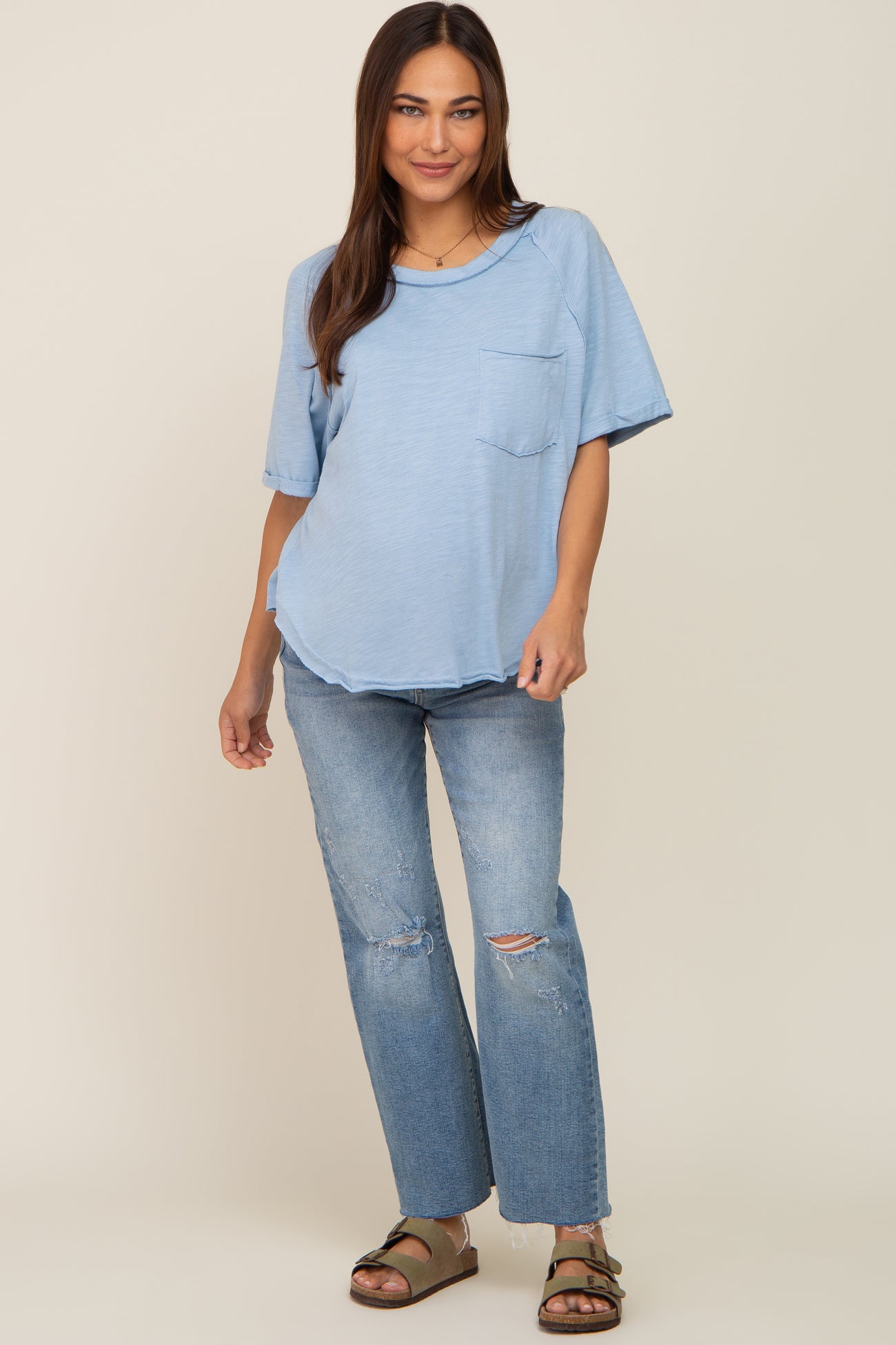 woman wearing light blue short sleeve pocket tee and distressed denim jeans with olive green sandals