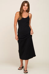 woman wearing a black spaghetti strap midi dress with a fitted bodice and flowy skirt