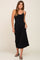 woman wearing a black spaghetti strap midi dress with a fitted bodice and flowy skirt