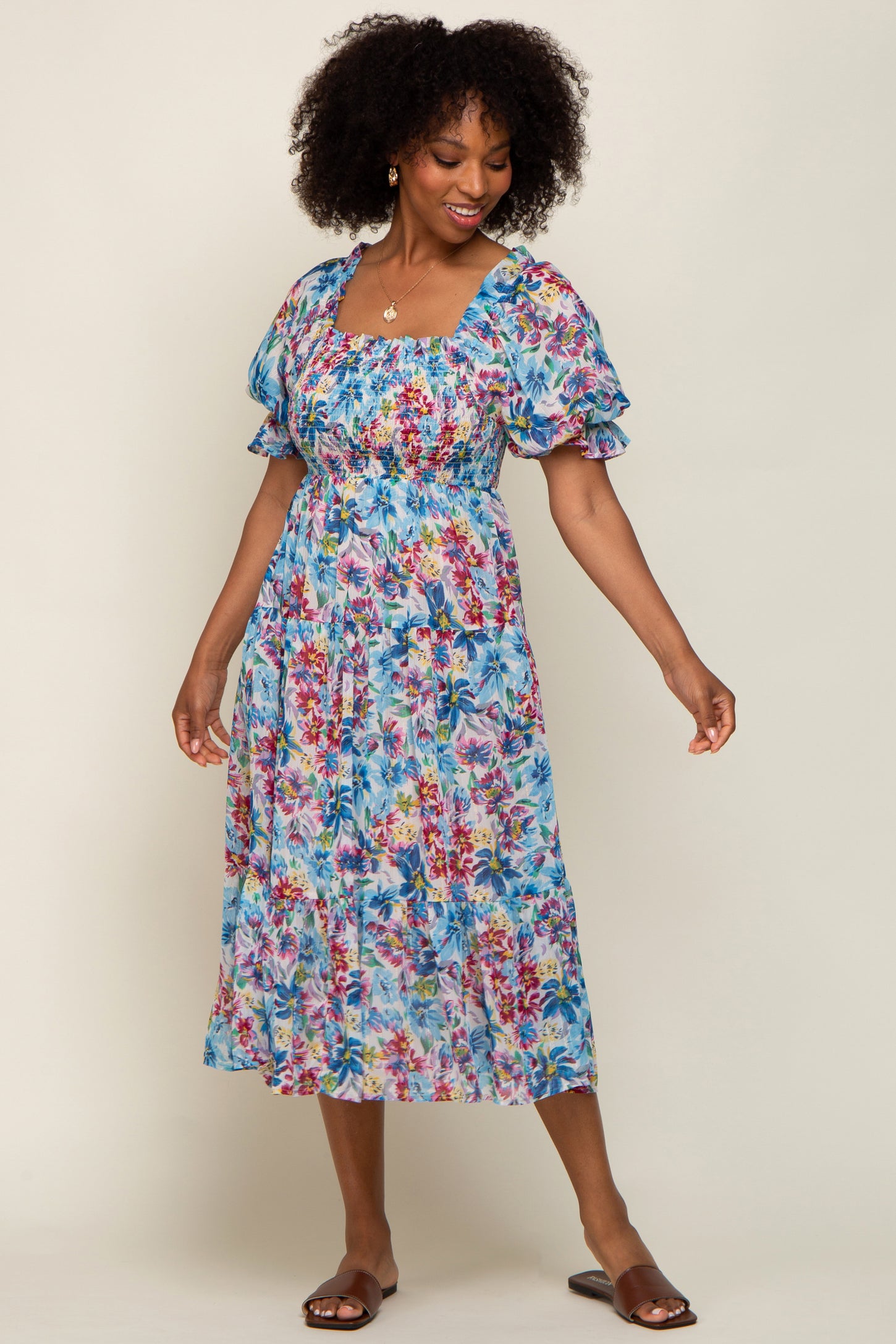 woman wearing a floral print maxi dress with puff sleeves and a fitted bodice, smiling and posing