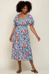 woman wearing a floral print maxi dress with puff sleeves and a fitted bodice, smiling and posing