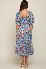 woman wearing a colorful floral maternity dress with puff sleeves and a smocked back, showing a relaxed fit