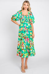 woman wearing a green floral mid-length dress with puff sleeves and a smocked bodice