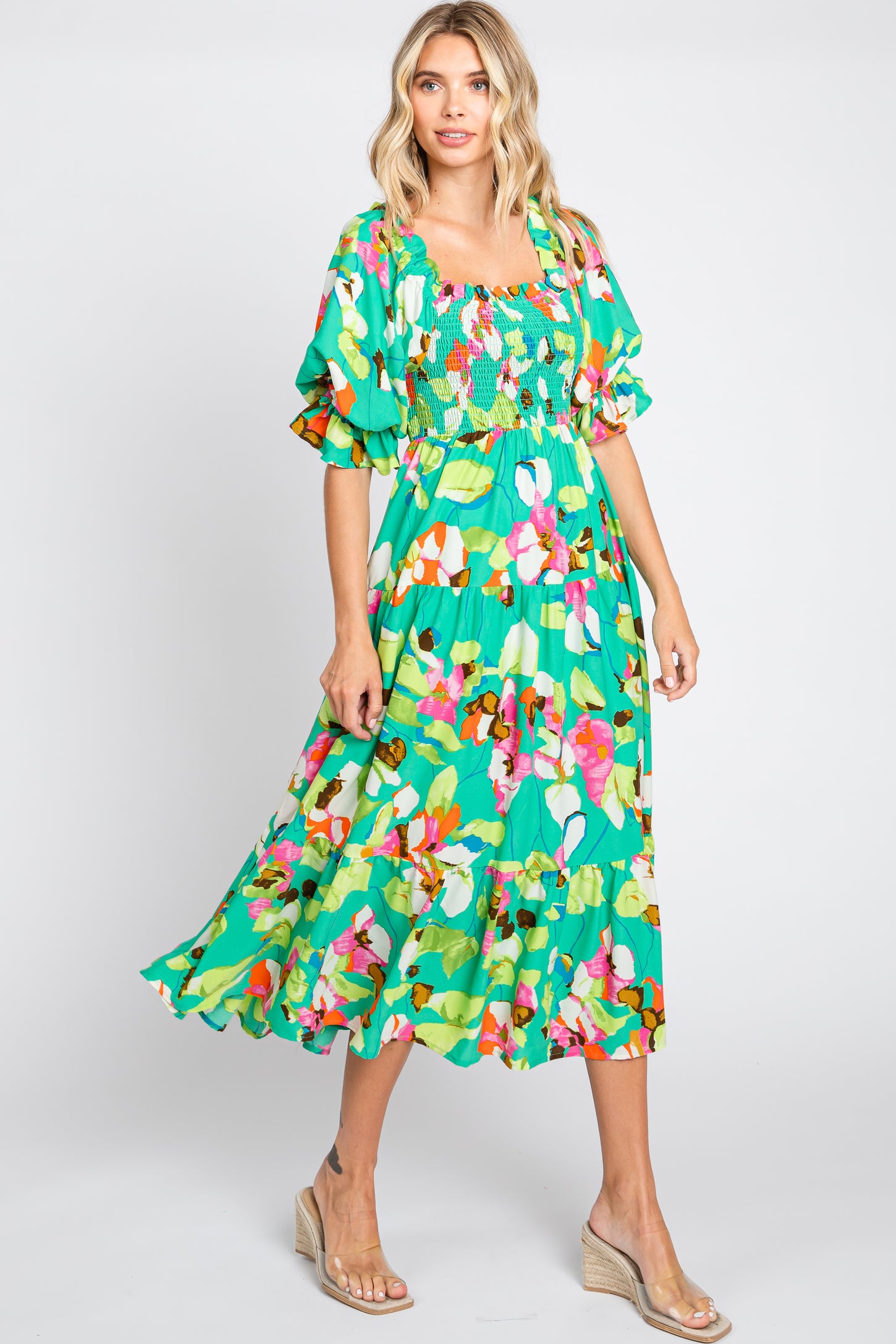 woman wearing a green floral midi dress with puff sleeves and smocked bodice