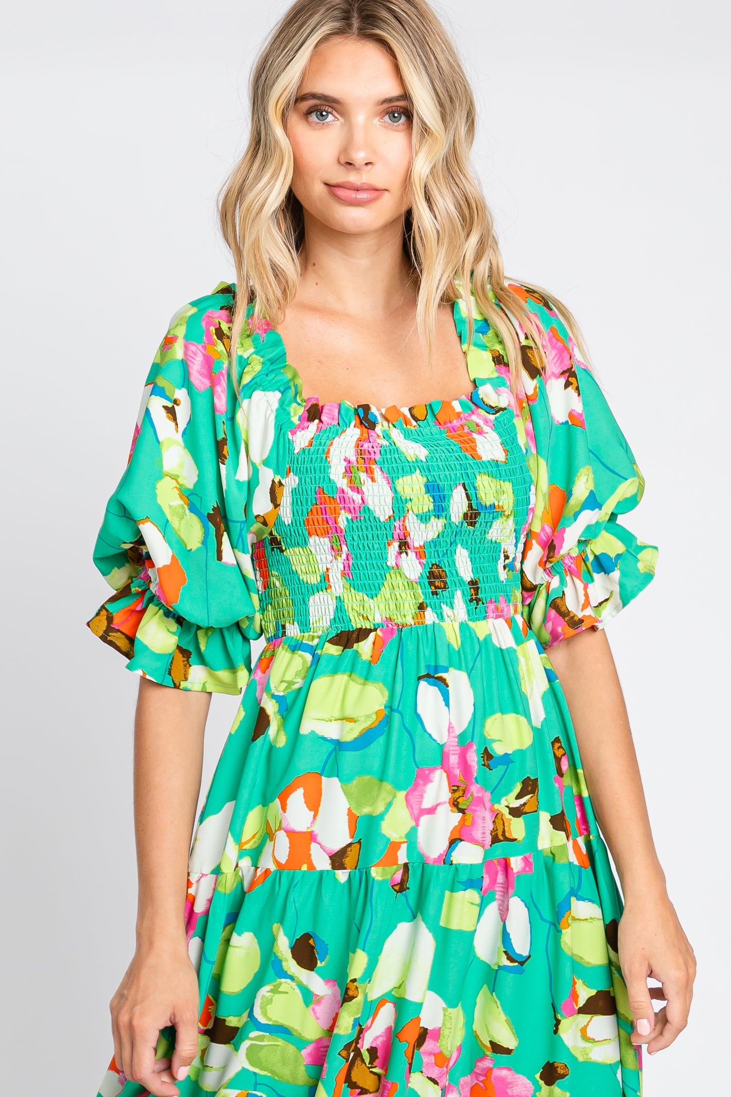 woman wearing a vibrant green floral dress with puff sleeves and a smocked bodice