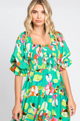 woman wearing a vibrant green floral dress with puff sleeves and a smocked bodice