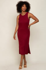 woman with curly hair wearing a sleeveless burgundy ribbed midi dress and tan slide sandals