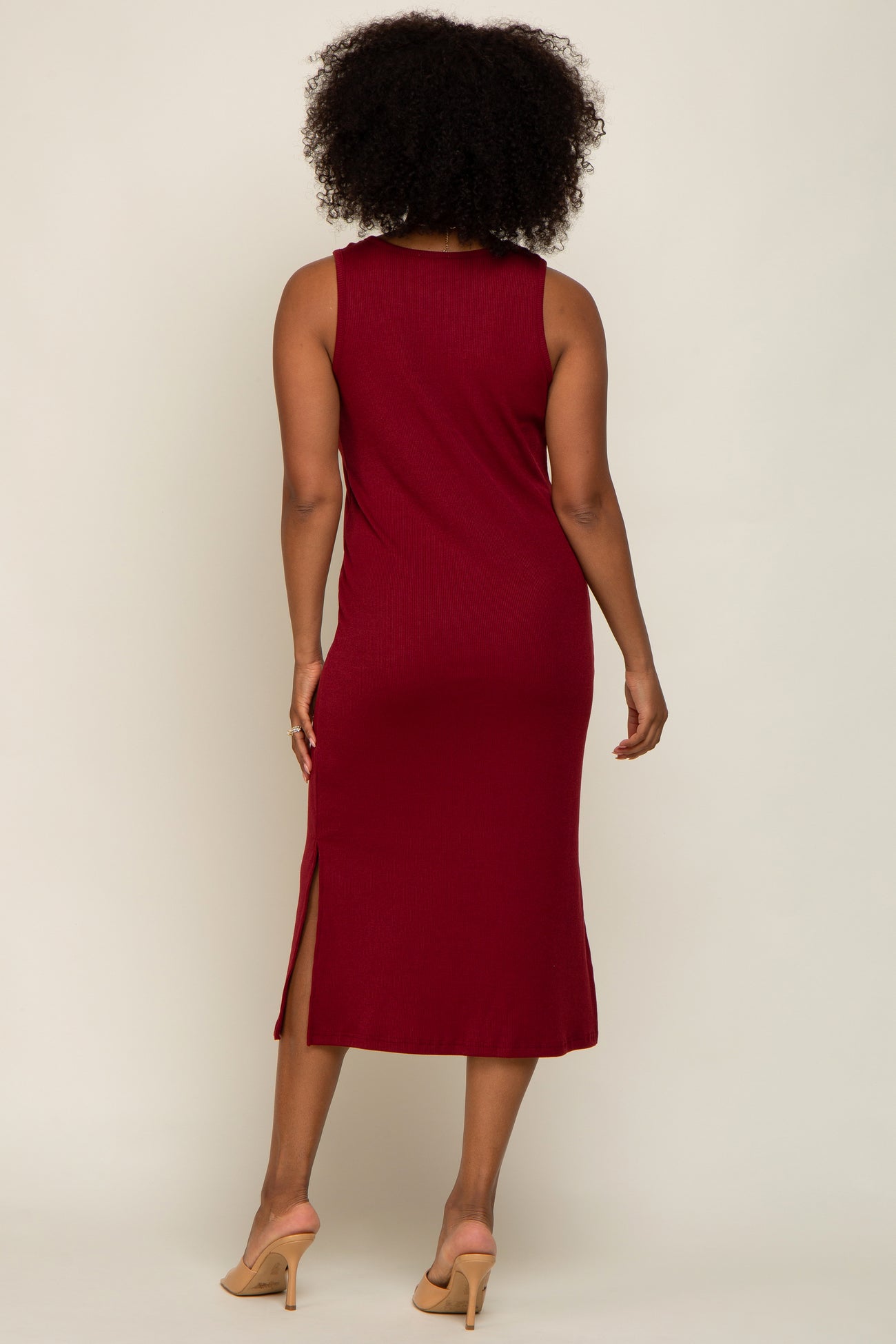 woman wearing a burgundy ribbed midi dress with side slits and a round neckline, shown from the back