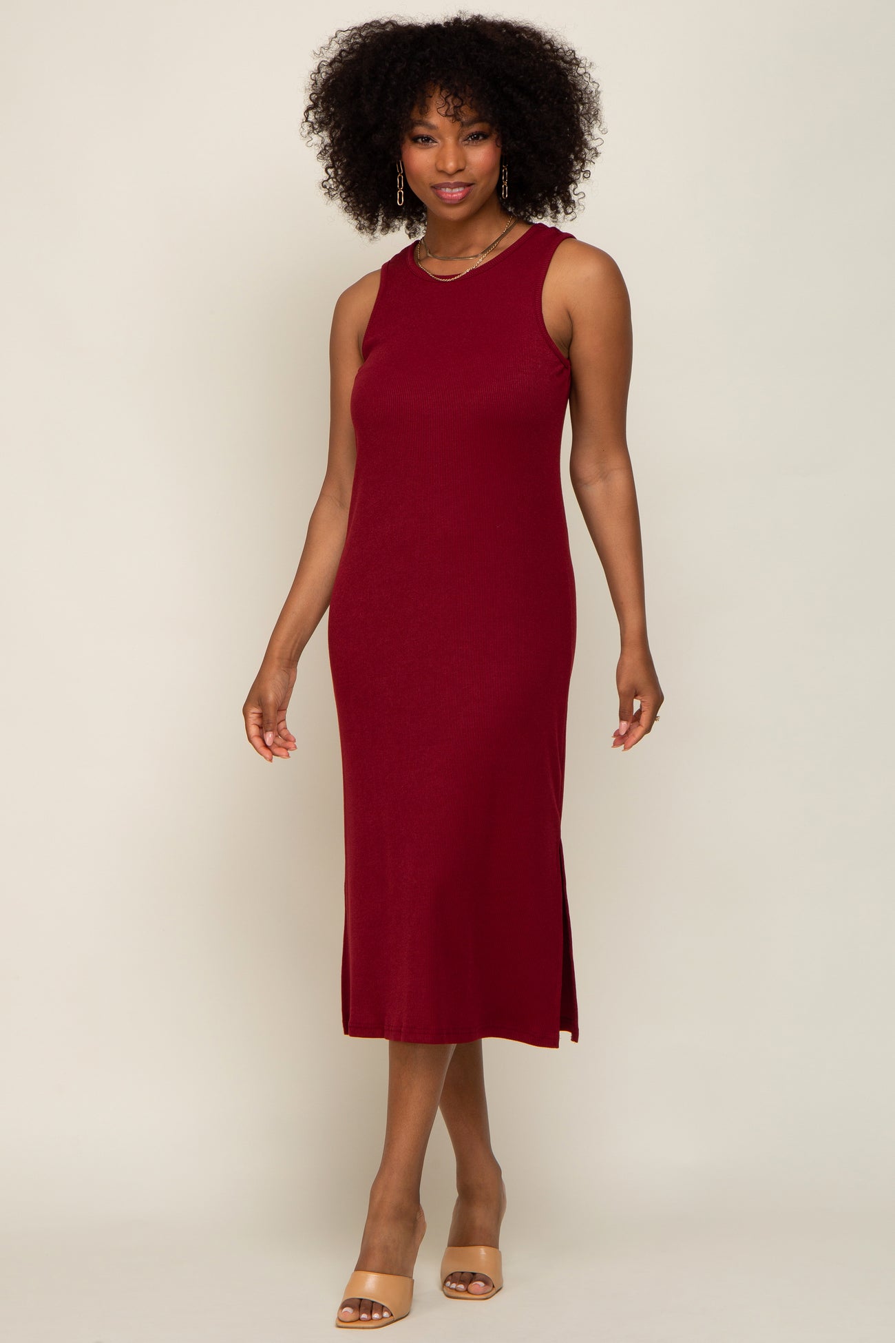 woman wearing a burgundy sleeveless ribbed midi dress with side slits and tan heeled sandals