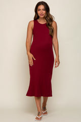 woman wearing a burgundy sleeveless ribbed maternity dress with a fitted silhouette and a baby bump visible