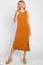Woman wearing a sleeveless burnt orange ribbed midi dress with side slits and tan platform sandals