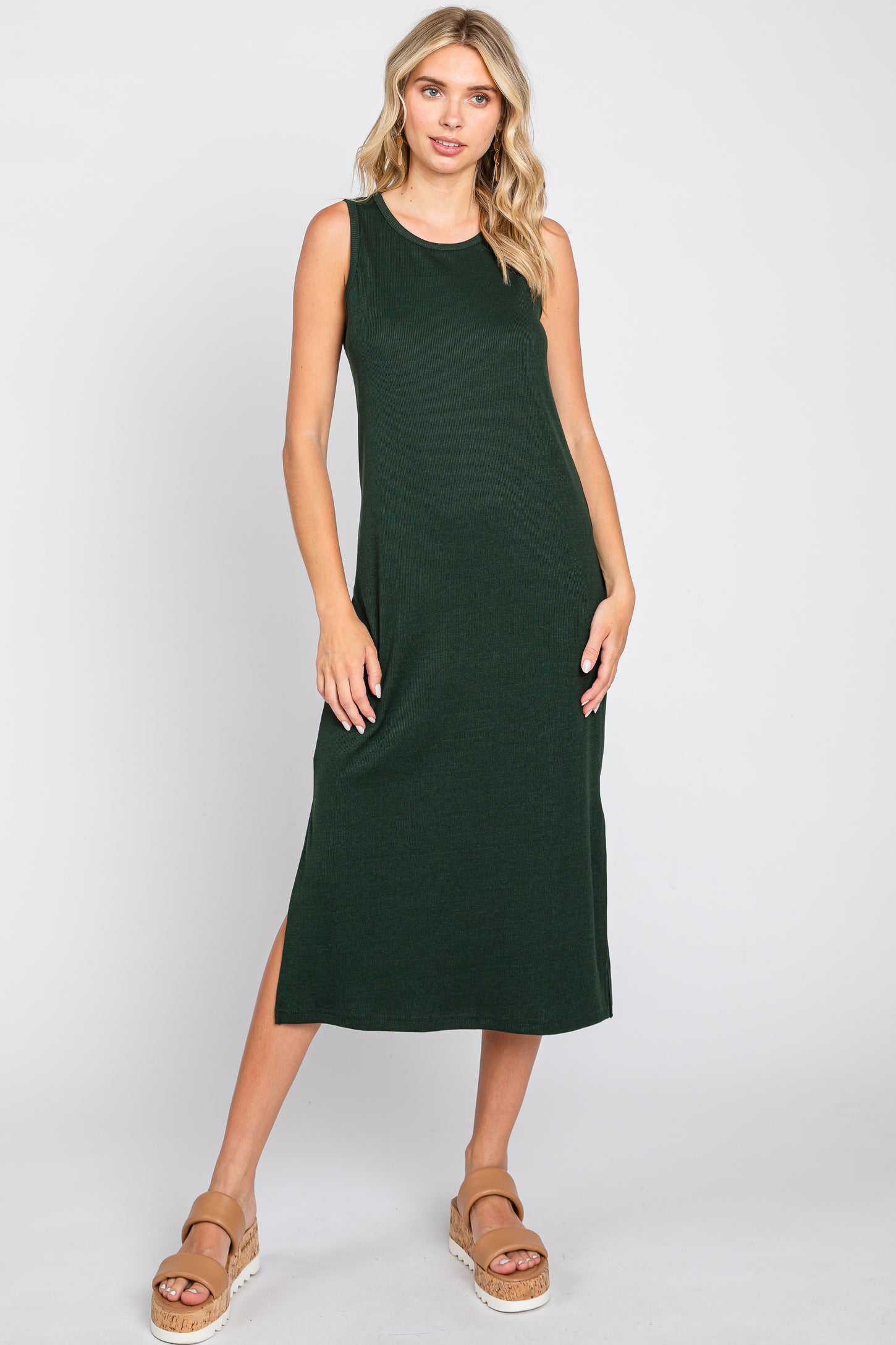 woman wearing a sleeveless dark green ribbed midi dress with side slits and tan platform sandals
