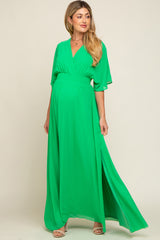 Pregnant woman wearing a green v-neck maternity maxi dress with short sleeves and a side slit