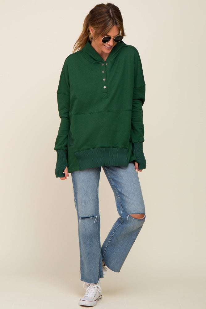 woman wearing oversized dark green button-up hoodie and distressed blue jeans with white sneakers