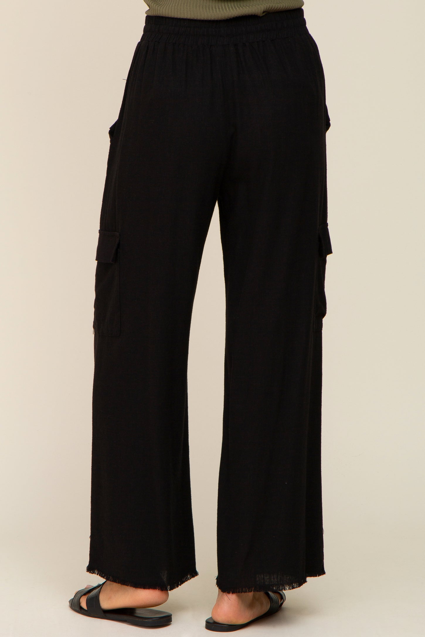 back view of woman wearing black wide leg cargo pants with elastic waistband and frayed hem