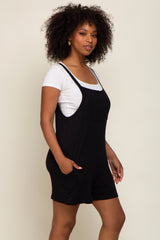 woman with curly hair wearing a black sleeveless romper over a white t-shirt